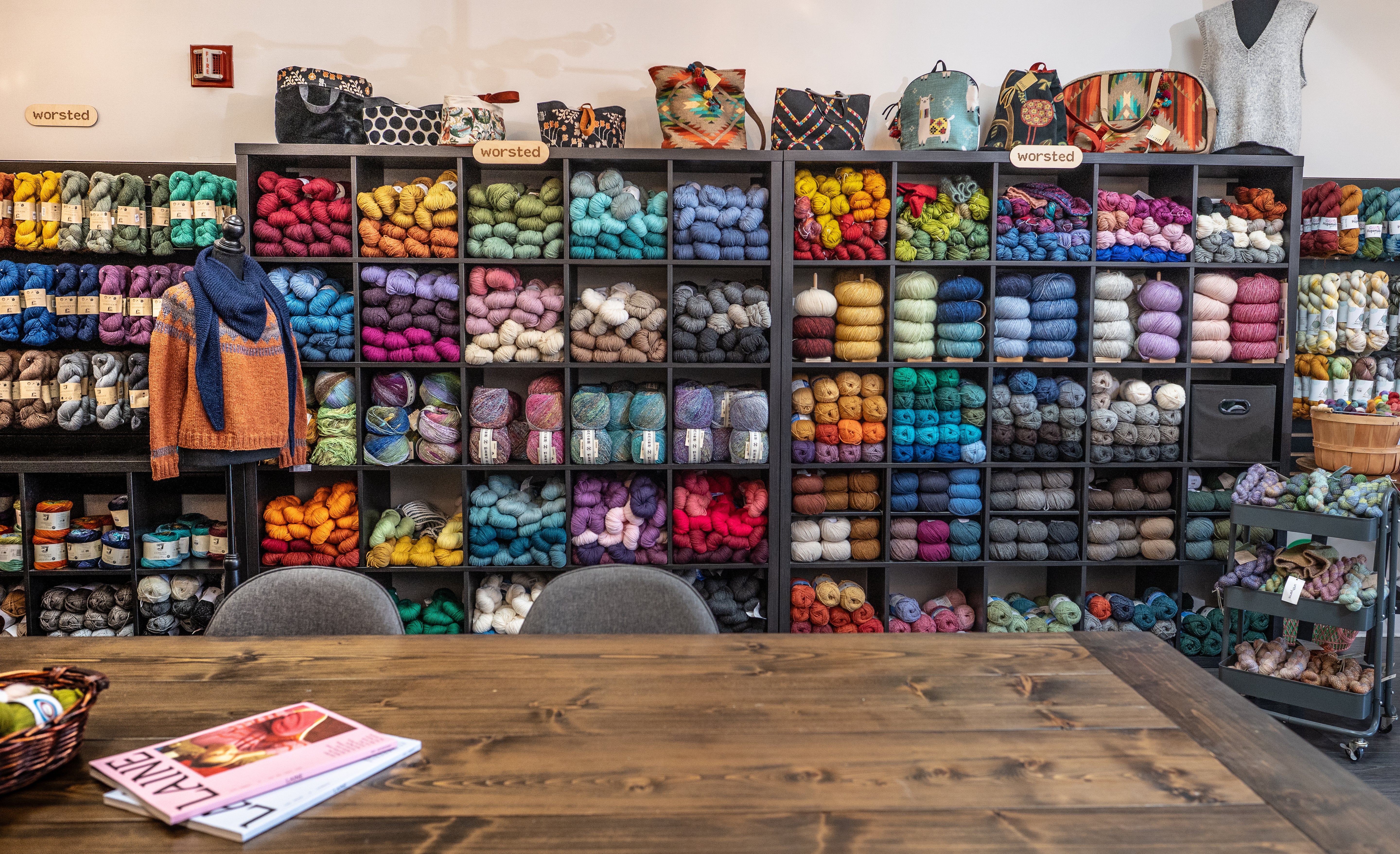 A yarn shop shelf filled with neatly stacked skeins in one color family, with labels facing outward